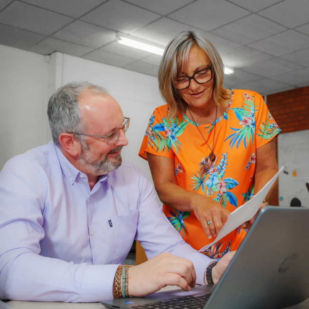 Man in a white shirt discussing a report with another person at a table.
