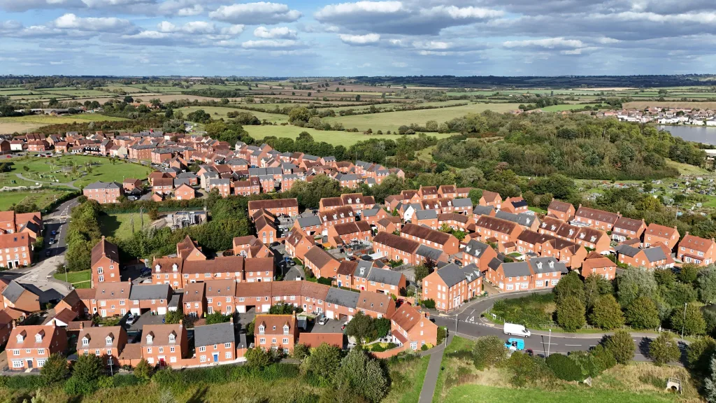 Aerial view of a town showcasing rooftops, streets, and green spaces under a clear blue sky.